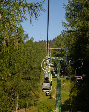 Scenic chairlift ride through the lush green forests of Monte San Vigilio in South Tyrol Italy