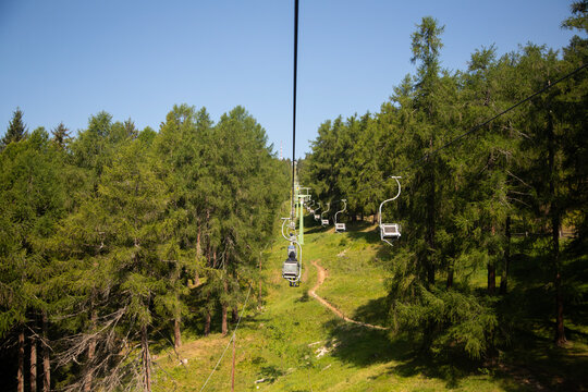 Scenic chairlift ride through the lush green forests of Monte San Vigilio in South Tyrol Italy