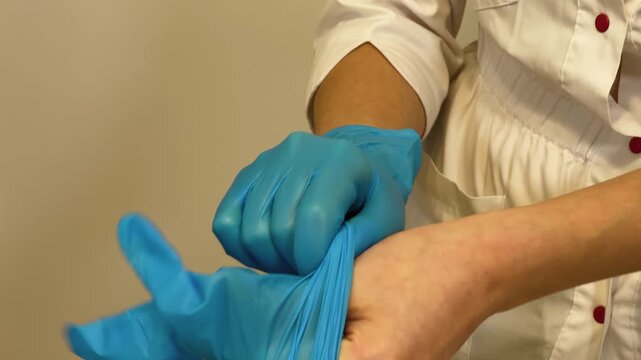 A female cosmetologist puts on gloves for a procedure