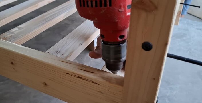 A carpenter drilling a wooden lumber with a screwdriver. Small business concept of professional tools.
