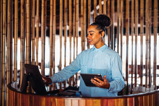 Successful female receptionist standing confidently at modern business front desk