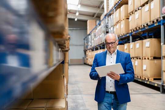 Male manager checks inventory on a tablet in a warehouse