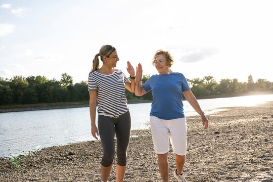 Young woman and senior woman share a high five while walking outside