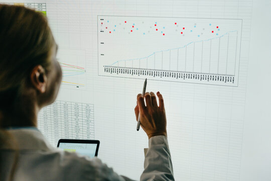 Businesswoman analyzes data chart on a large digital screen