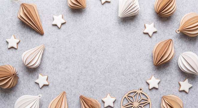 Paper craft ornaments and minimalist decorations forming a frame on grey background for Christmas flat lay