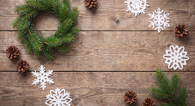 Pine wreath and white wooden snowflakes on rustic table for Christmas flat lay background with copy space