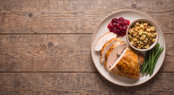 Plated Thanksgiving holiday dinner with sliced roasted turkey stuffing and cranberry sauce