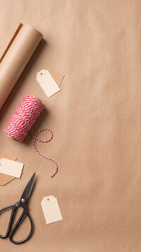 Festive gift wrapping preparation with brown kraft paper rolls sharp scissors and colorful twine rolls