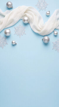Winter holiday christmas background featuring shiny baubles ornaments and a white decorative scarf on pastel blue