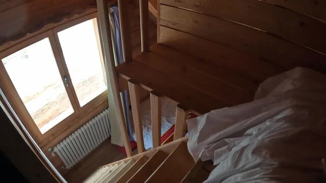 Rustic wooden cabin interior looking down the stairs to a bedroom. Cozy winter holiday accommodation in a mountain chalet.