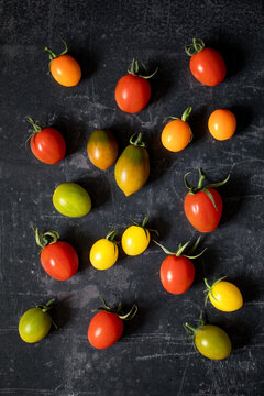A variety of heritage tomatoes, in red, orange, yellow and green, over old chalkboard background.