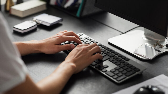 Administrator's hands are positioned on a computer keyboard, with a name badge and several office supplies nearby