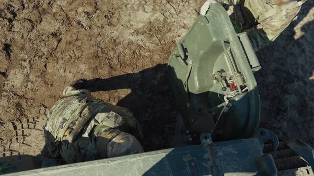 Overhead view of soldiers pulling a wounded comrade out of an armored vehicle hatch during an evacuation