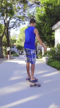 Boy riding longboard between houses on straight path