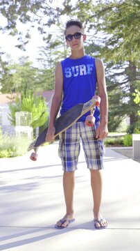 Person with longboard under hand posing on concrete path