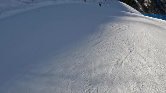 Fast POV downhill skiing along a blue safety net. Dynamic winter sports action on a sunny alpine slope. First person view of an active mountain vacation.