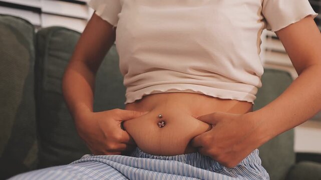 Overweight woman body with hands touching belly fat