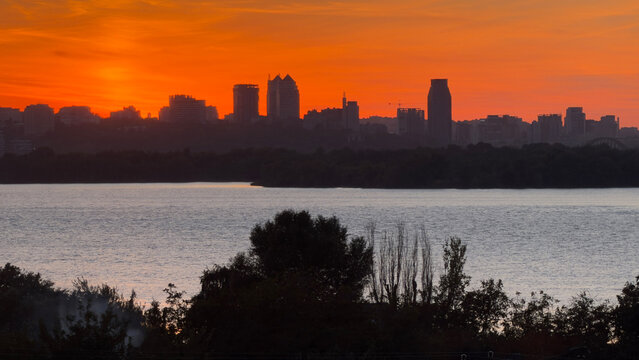 Dnipro City skyline with river, dramatic orange sunset dusk landscape