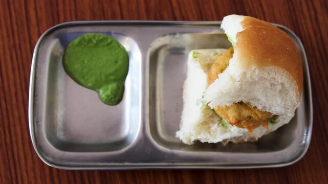 Fresh Vada Pav With Spicy Green Chutney Served on Metal Plate for breakfast