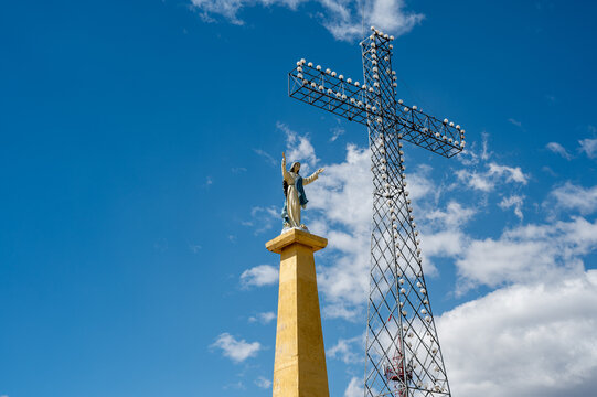 Huancayo, Peru (Per&uacute;) : The Virgin Mary statue stands beside the illuminated Cruz de la Paz on Cerro Achkamarca above Huancayo. The monumental metal cross and Marian statue rise against a blue sky.