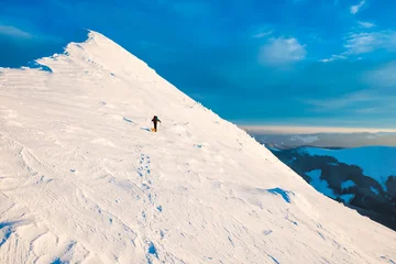 Man mountaineer with dog climbing on a slope at snowy mountain top in sunset evening © Pavlo Vakhrushev