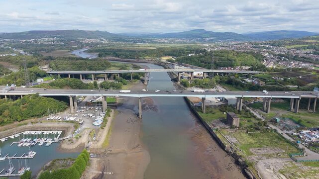Bridges Crossing River Neath with Busy Flowing Traffic with Marina and Open Landscape of South Wales in Background. Aerial Footage.