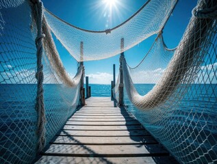 Naklejka premium Wooden pier with rope netting leads to calm blue ocean. Sunny day with bright sky, sea horizon. Relaxing summer vacation scene featuring maritime structure, fishing nets on seaside dock. Peaceful