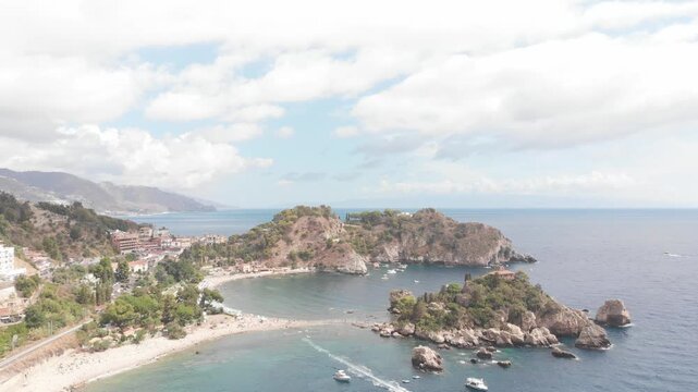 Aerial drone descending shot approaching Isola Bella off the coast of Taormina, Sicily, with the Mediterranean Sea surrounding the island.