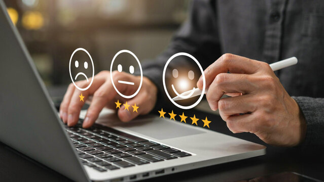 Customer typing on laptop during online survey with glowing satisfaction icons and five star rating against blurred background