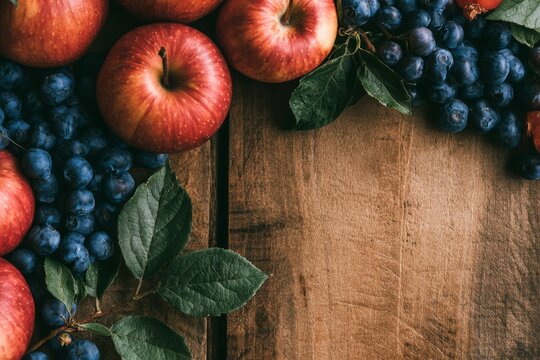 Early autumn flat lay, ripe red apples, dark blueberries, arranged around the outer borders of the frame