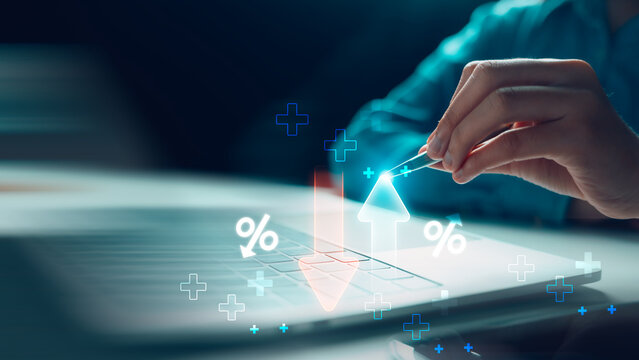 Businessman touching rising arrow and red falling arrow on laptop keyboard for cost reduction, business profit growth, finance budget management, and efficiency investment concept.