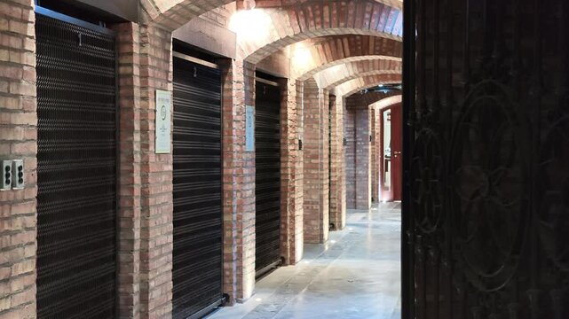 Modern underground wine cellar features repeated brick archways, vaulted ceilings and enclosed storage rooms along a long corridor, with industrial doors and masonry details, lateral slide reveal.