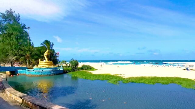 Golden Naga statue beside river tropical beach turquoise waves Karon Phuket Thailand.