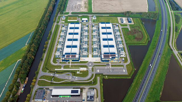 Aerial view of the Microsoft datacenter complex surrounded by green fields, canals, and highway infrastructure in Middenmeer, Noord-Holland, Netherlands.
