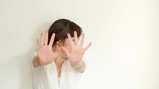 unhappy 30s adult southeast asian woman showing rejecting hand sign and arm crossing gesture for saying no
