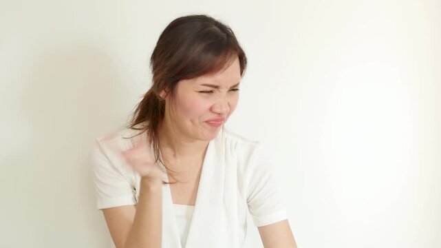Unhappy 30s Southeast Asian woman reacting to a bad smell indoors, grimacing and covering her nose