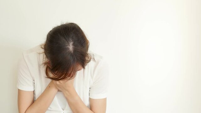 Sick 30s adult southeast asian woman having toothache, tooth decay, holding her cheek in pain with a grimace, painful facial expression