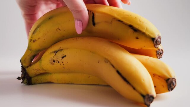 Hand pulling a ripe yellow banana from a bunch, showing the simple action of separating fresh tropical fruit. High quality 4k footage