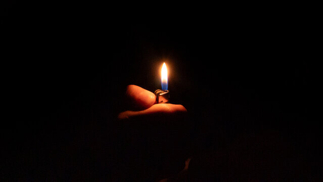 hand holding a lighter in the darkness