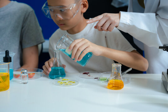 Mother and two sons pouring colorful liquid into glass beakers.