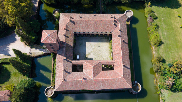 Aerial view of Castello di Peschiera Borromeo, a historic moated castle with a central courtyard and terracotta roof, surrounded by greenery and water in Peschiera Borromeo, Lombardia, Italy.
