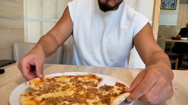 Close Up Athletic Man Hands Reaching for Fresh Baked Tuna Pizza Slices at Restaurant Table Fast Casual Dining Concept