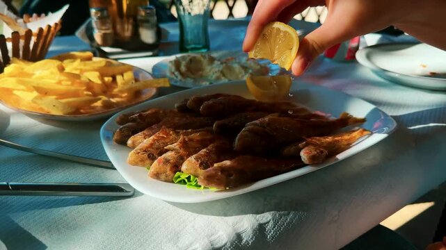 Squeezing Lemon Over Fried Fish Served With French Fries In Restaurant