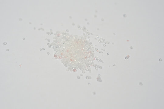 scattered pile of small clear silica gel beads on a plain white surface