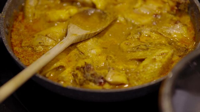 Boiling Chicken Pieces Simmering In Yellow Curry Sauce Inside Pan