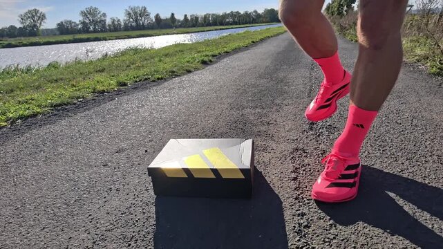 CZECH REPUBLIC &ndash; 29.9.2026: Runner wearing bright pink adidas Adizero Adios Pro 5 running shoes standing on an asphalt country road. Close-up of modern carbon racing shoes during outdoor running train