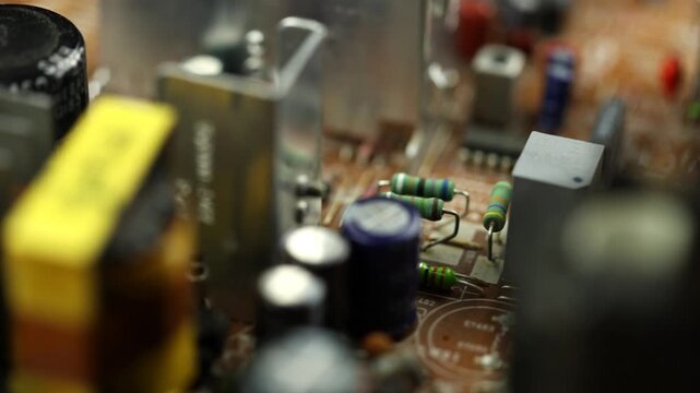 Macro camera gliding smoothly above retro electronic circuit board densely packed with capacitors, resistors, transformers, integrated circuits, aluminum heat sinks and vintage components