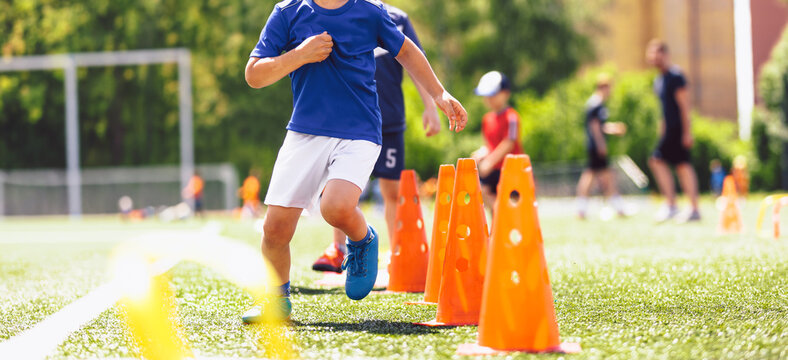 Junior Soccer Player Running Through Orange Agility Cones During Outdoor Training Session - Youth Football Speed and Coordination Drill