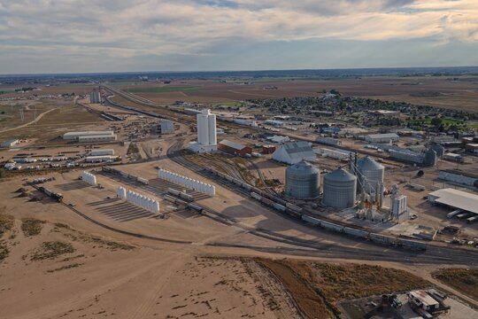 Aerial view of grain elevators and industrial silos situated near railroad tracks in the rural landscape of Eaton, Colorado, United States.