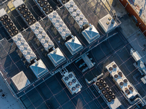 Aerial view of a data center rooftop featuring numerous industrial cooling units and HVAC systems arranged in rows on a flat roof in Warszawa, Mazowieckie, Poland.